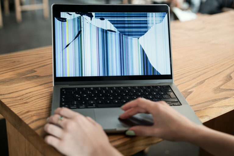 Laptop screen cracked with colorful lines, hands on touchpad, Singapore repair cost