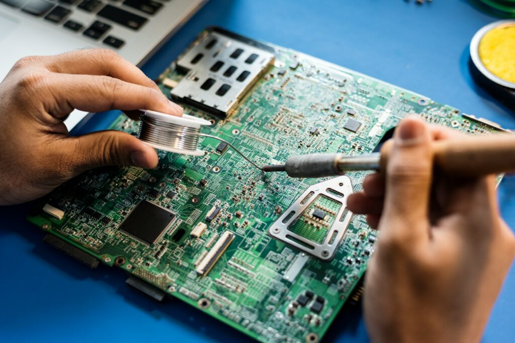 Laptop Repair Cost in Singapore - Technician soldering a laptop motherboard, essential for Singapore laptop repair.