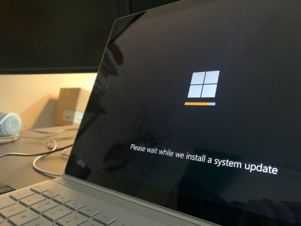 Laptop screen showing "Please wait while we install a system update" during Windows update.